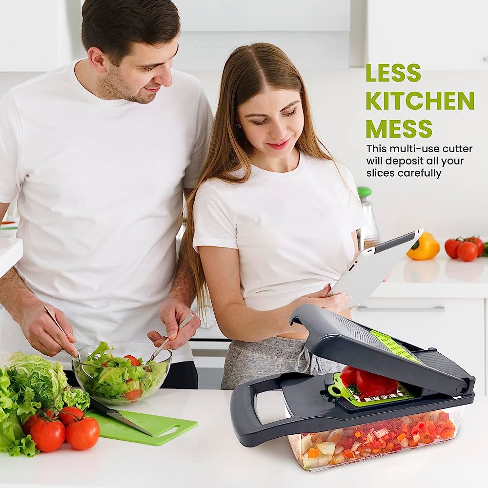 Person using a gray and green vegetable chopper to dice a green bell pepper into a clear container, with tomatoes, onions, and another green bell pepper on a white counter. The background shows a kitchen.